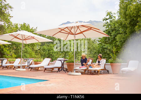 Coppia matura rilassarsi sulle sedie a sdraio alla piscina resort Foto Stock