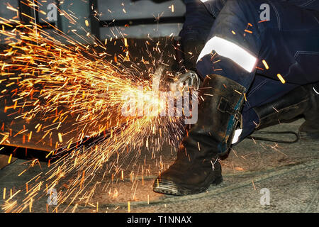 Scintille luminose dal taglio di metallo con un carbonio-macchina slave in officina camera. Lavoro con lo strumento in produzione. Foto Stock