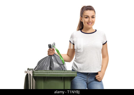 Giovane ragazza lanciando un sacco dei rifiuti di plastica in un contenitore isolato su sfondo bianco Foto Stock