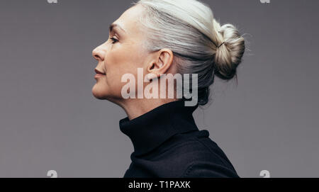 Vista laterale del senior donna su sfondo grigio. Vista di Profilo di donna matura in nero casuals. Foto Stock