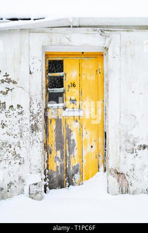 Giallo antico cottage di legno porta nel villaggio Leadhills nelle prime ore del mattino la neve. Scotlands secondo villaggio più alto. South Lanarkshire, Scozia Foto Stock