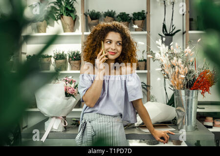 Un fioraio che riceve la chiamata dal fidanzato mentre avente una piccola pausa dal lavoro Foto Stock
