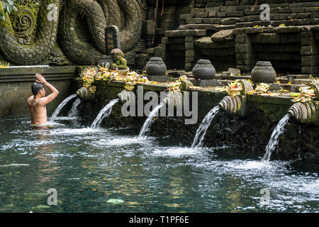 Bali, Indonesia - 22 gennaio 2019: il giovane uomo che prega nella primavera sacra di acqua pura Tirta Empul temple a Tampa, Bali, Indonesia. Foto Stock