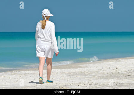 Bella donna matura per ascoltare musica mentre facendo una piacevole passeggiata sulla spiaggia. Foto Stock