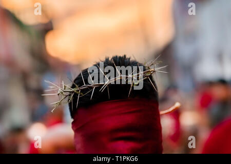 Un cattolico con cappuccio penitente è visto indossare una corona di spine durante la settimana Santa processione in Atlixco, Messico. Foto Stock