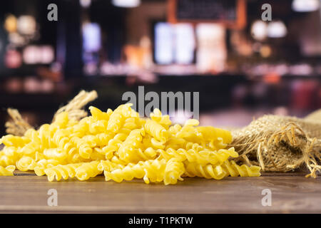 Lotto di pezzi di materie italitan pasta gialla torti sulla stoffa di iuta con ristorante in background Foto Stock