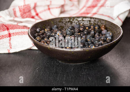 Sacco di tutta la secca di bacche di ginepro Semi sul grigio pietra Foto Stock