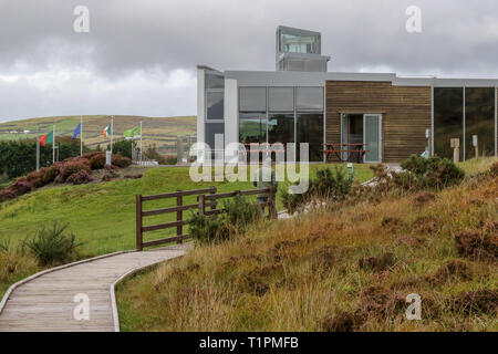 Uomo che cammina su una passerella di legno attraverso bogland in Irlanda towars Ballycroy il Centro Visitatori del Parco Nazionale. Foto Stock