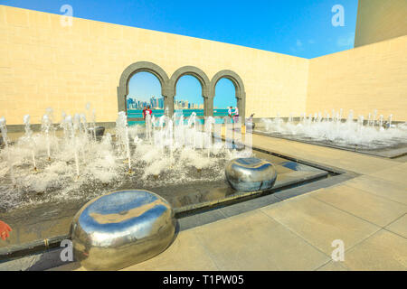 Doha, Qatar - 16 Febbraio 2019: persone turisti nel cortile del Museo di Arte Islamica con fontane, panchine e finestre ad arco con vista di apertura su Doha Foto Stock