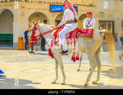 Doha, Qatar - 20 Febbraio 2019: primo piano della polizia a cavallo in abiti tradizionali al Souq Waqif bianco di equitazione cavalli arabi. Turistici popolari Foto Stock