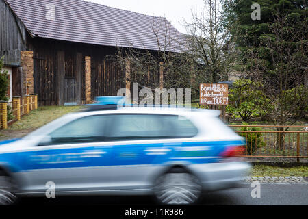 28 marzo 2019, in Sassonia, Mühlrose: Vista su una macchina della polizia in un giardino frontale del villaggio Mühlrose nella Lausitz, in cui un cartello con la scritta "si seppellire il carbone, si seppellire il nostro paese". Mühlrose è uno degli ultimi villaggi del distretto Lusatian per dare modo a carbone marrone, che è quello di essere dragati all inizio del 2030s. Lausitz Energie Bergbau AG si aspetta un volume di produzione di 150 milioni di tonnellate di carbone. Il nuovo mulino rose si trova quindi nel ciclo di sette chilometri di distanza. Foto: Oliver Killig/dpa-Zentralbild/dpa Foto Stock