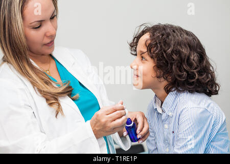 Medico dando un bambino la medicina omeopatica Foto Stock