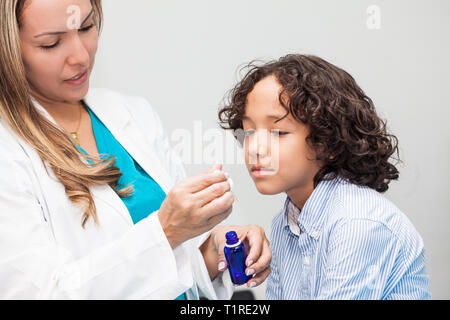 Medico dando un bambino la medicina omeopatica Foto Stock