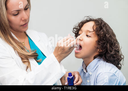 Medico dando un bambino la medicina omeopatica Foto Stock