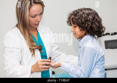 Medico dando un bambino la medicina omeopatica Foto Stock