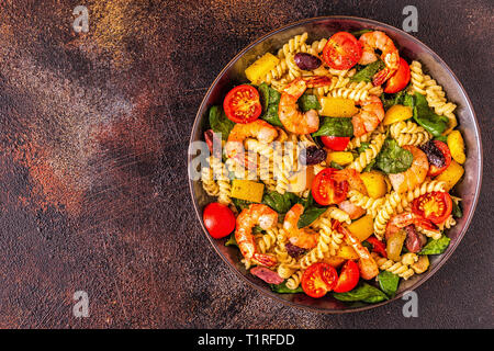Fusili insalata di pasta con gamberetti, pomodori, peperoni, spinaci, olive, vista dall'alto. Foto Stock