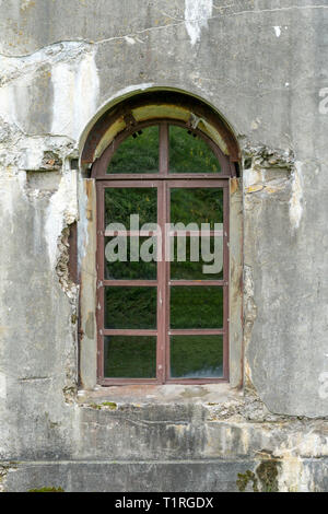 Vecchio danneggiato intonacata parete in mattoni con finestra. Foto Stock