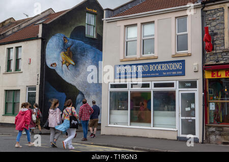 I membri del pubblico attraversando il Nord San a un murale di un uccello gigante dipinta su un muro di casa in Upfest streetart festival Bedminster Bristol Foto Stock