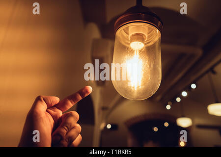 La mano di raggiungere per un vintage lampadina. Foto Stock