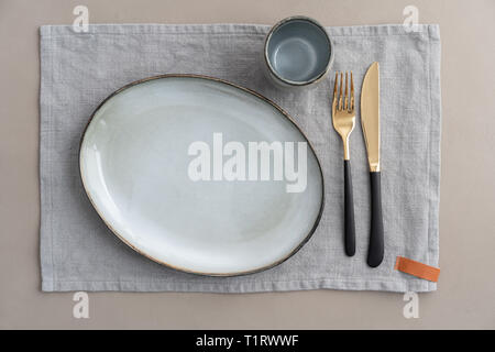 Svuotare tavolo da pranzo luogo impostazione con ceramica grigia e oro e nero posate Foto Stock