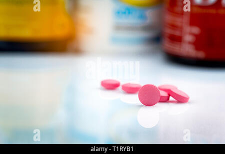 Round rosa compresse pillola su sfondo sfocato del flacone di farmaco. Antidolorifico La medicina. Uso di farmaci per il trattamento il mal di testa di emicrania. I prodotti farmaceutici. Pharma Foto Stock