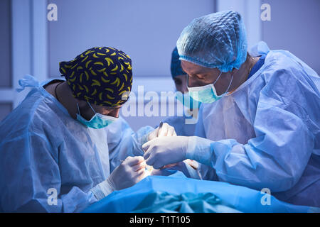 Preparazioni di chirurgia. Il team chirurgico preparare loro paziente per la chirurgia regolazione della maschera di ossigeno sulla faccia al theare operativo. healthcare surgery Foto Stock
