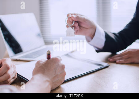 L'uomo la scrittura e la firma sul contratto di casa dopo la finitura di vendita e acquisto di casa con home agenzia banchiere Foto Stock