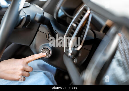 La donna a partire auto a motore con il pulsante, vista da vicino. Concetto di vettura senza chiave start Foto Stock