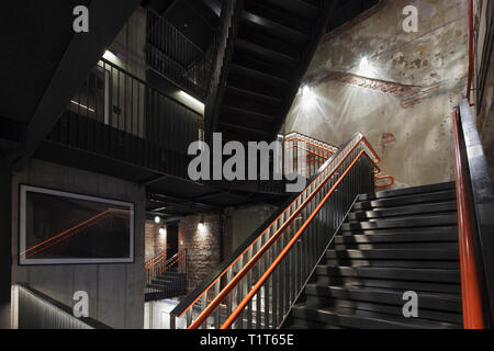 Metallo nero scala con corrimano arancione. Sentralen, Oslo, Norvegia. Architetto: Atelier Oslo & Kima Arkitektur, 2016. Foto Stock