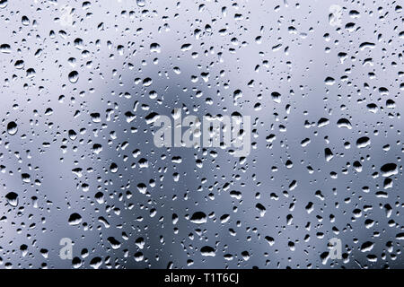 Gocce di pioggia su una finestra su una giornata uggiosa Foto Stock