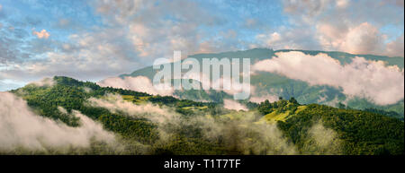 Il paesaggio tipico della campagna georgiana nel Caucaso pedemontana all'alba attraverso la mattina nuvole basse vicino Nikortsminda, Racha regione della Georgia Foto Stock