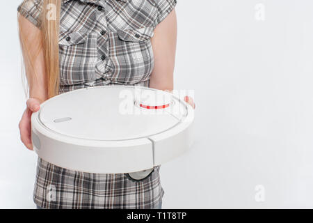 Robot aspirapolvere nelle mani della donna. robotico assistente domestico concetto. Foto Stock