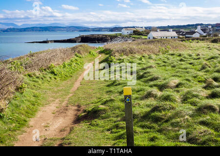 Percorso costiero di Anglesey e posto indicatore di direzione sulla costa gallese con vista sulle montagne lontane. Moelfre, Isola di Anglesey, Galles, Regno Unito, Gran Bretagna Foto Stock