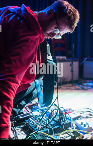 Un uomo suona musica sperimentale con una chitarra e una moltitudine di effetti processori, durante un assolo di prestazioni. Foto Stock