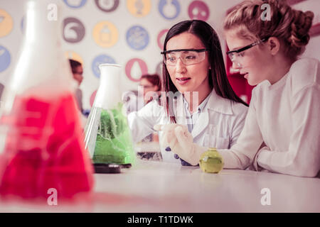 Con i capelli lunghi donna che lavorano nella scuola e avente esperimento chimico Foto Stock