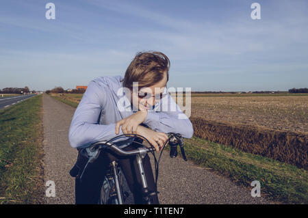 Esaurito l'uomo in abbigliamento classico sulla bicicletta è tenuto dalla rottura la pedalata Foto Stock