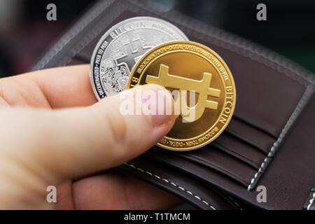 Uomo con la versione fisica di oro e di argento bitcoins. Foto Stock