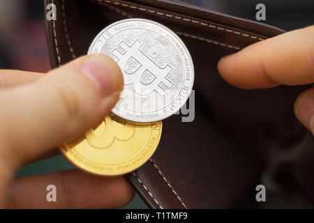 Uomo con la versione fisica di oro e di argento bitcoins. Foto Stock