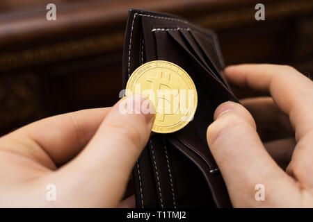 Uomo con la versione fisica di golden bitcoin. Foto Stock