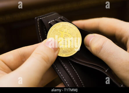 Uomo con la versione fisica di golden bitcoin. Foto Stock
