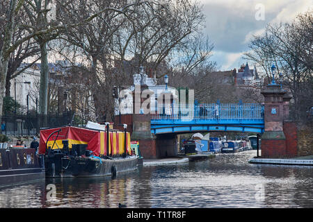 Londra Little Venice AREA DI PADDINGTON Grand Union Canal e Regents Canal di rosso e di giallo BARGE accanto al ponte Blu Foto Stock