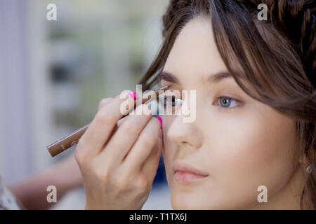 Bella giovane donna fare il trucco a un professionista di truccatore. Correzione e colorazione delle sopracciglia, close-up Foto Stock