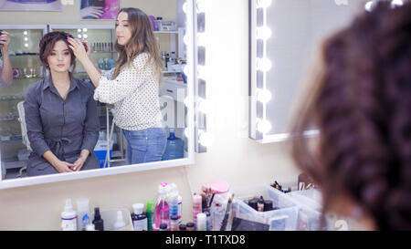 La stilista truccatore facendo il trucco e capelli in un salone di bellezza. Professionale di make-up, maestro di creazione dell'immagine. Foto Stock