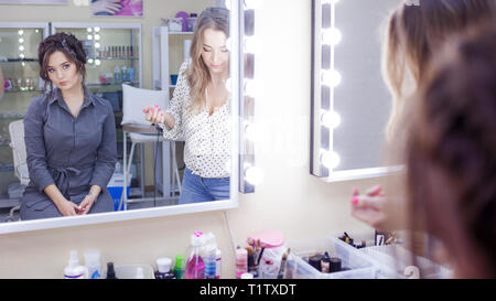 La stilista truccatore facendo il trucco e capelli in un salone di bellezza. Professionale di make-up, maestro di creazione dell'immagine. Foto Stock