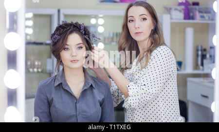 La stilista truccatore facendo il trucco e capelli in un salone di bellezza. Professionale di make-up, maestro di creazione dell'immagine. Foto Stock