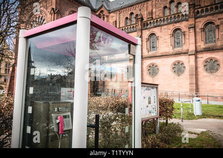 Freiburg im Breisgau, Germania - 31 dicembre 2017: Deutsche Telekom phone booth davanti a una chiesa nel centro storico della città in un giorno di inverno Foto Stock