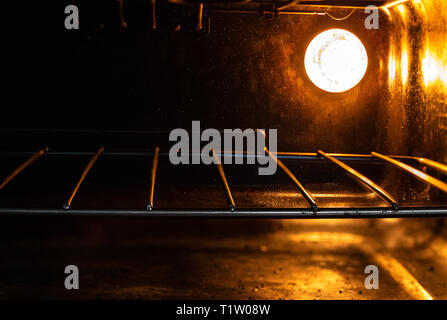 All'interno del forno/grill/fornelli con arancio brillante luce illuminante sul reticolo metallico. Grill/forno apparecchio, fornello Foto Stock