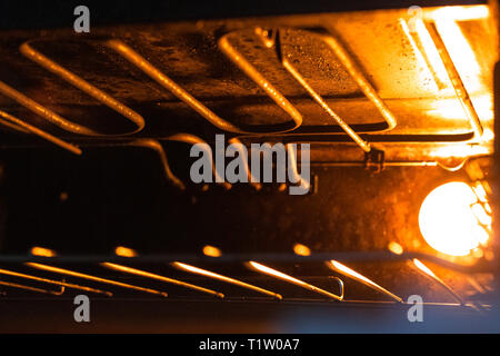 All'interno del forno/grill/fornelli con arancio brillante luce illuminante sul reticolo metallico. Grill/forno apparecchio, fornello Foto Stock