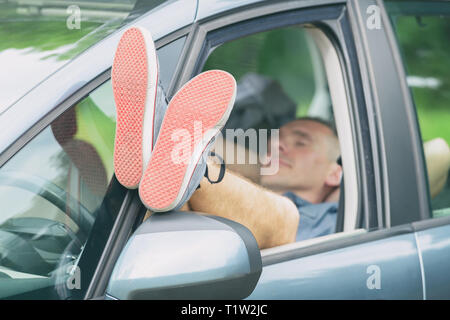 Uomo dorme in auto prima della successiva parte del viaggio Foto Stock