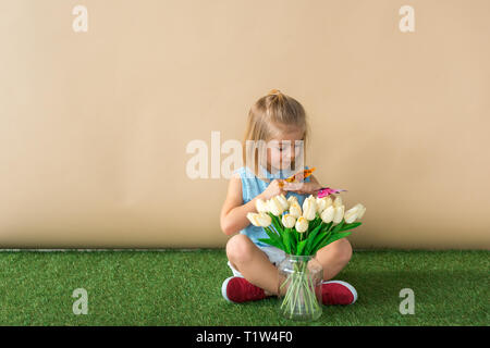 Bambino seduto con le gambe incrociate e tenuta a farfalla giallo Foto Stock